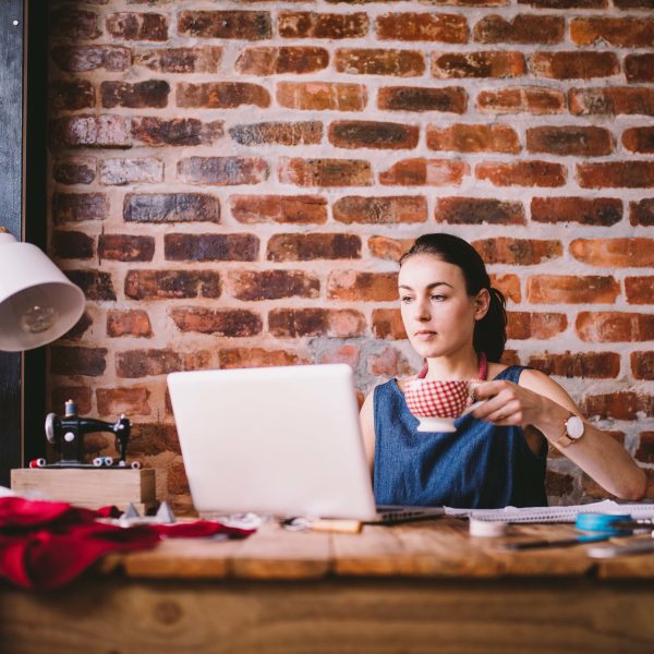 Young businesswoman working on laptop and drinking coffee